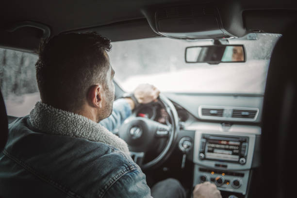 One man, a handsome young man traveling through a snow-covered forest, sits behind the wheel and enjoys a winter ride.