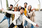 Big group of happy friends stands together on city street with raised arms - Multiracial young people having fun outside - Volunteer with hands up showing teamwork spirit - Community and friendship