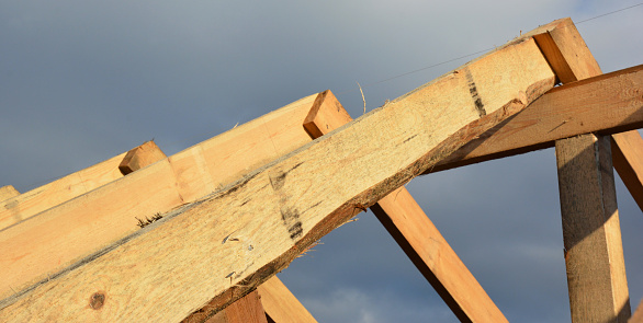 Roofing construction during the roof framing with a close-up of wooden roof truss, rafters and ridge beam.