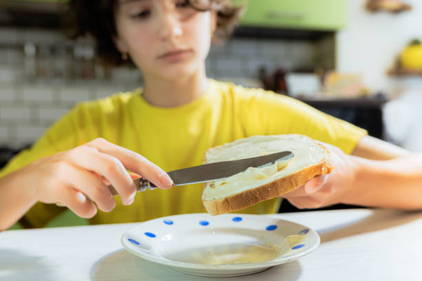 étaler du fromage à la crème sur du pain grillé pour une collation - pain tranché photos et images de collection