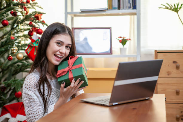 istock Happy young woman showing a Christmas present box on her notebook. 1364225788