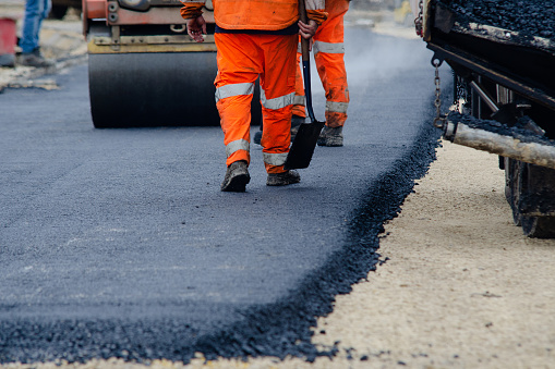Roadworkers placing hot tarmac new road construction project