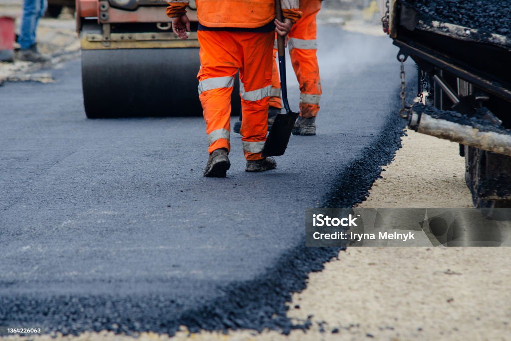 Roadworkers placing hot tarmac new road construction project Road Construction Stock Photo