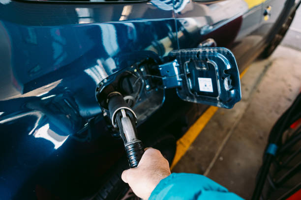 sosteniendo con la mano una manguera conectada a un automóvil hecho de combustible lpg (gas licuado de petróleo) en una estación de servicio en un automóvil azul metálico. repostaje, gasolinera, ecología, transporte y concepto ecológico. - lpg fotografías e imágenes de stock