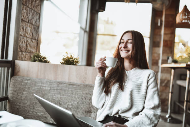 istock Smiling Beautiful Female Drinking Coffee While Working On Laptop In Bar 1364228805