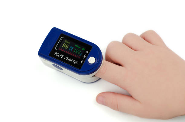 Pulse oximeter on a child's finger on a white background. Saturation 98 and pulse 122 in a child Pulse oximeter on a child's finger on a white background. Saturation 98 and pulse 122 in a child saturated color stock pictures, royalty-free photos & images