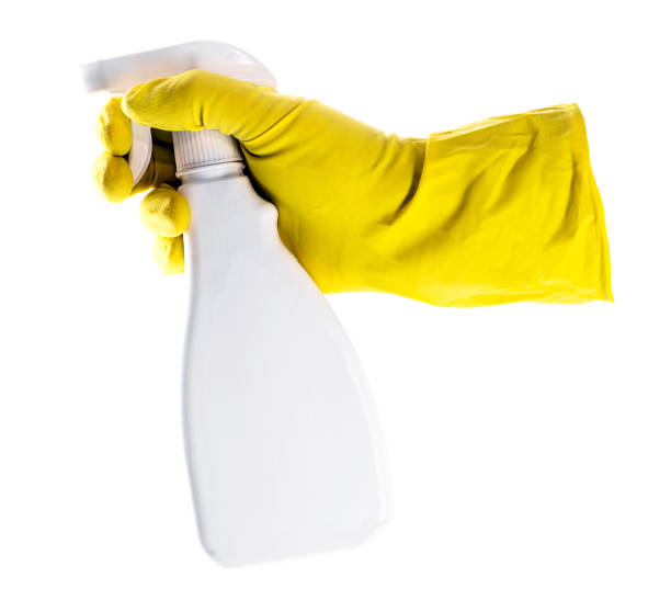 main avec gant de protection en latex jaune tenant le flacon pulvérisateur, spray spray polyvalent sur fond blanc isolé - protective glove washing up glove cleaning latex photos et images de collection