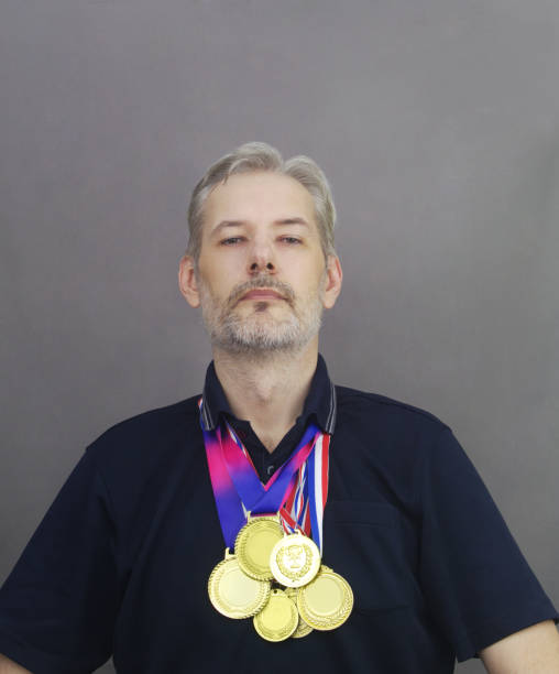 istock Middle age men with many gold medals on gray background. 1364229794