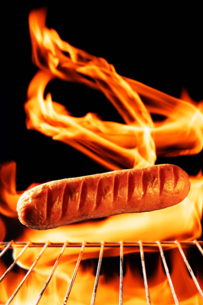 Grilled sausages with flames on a dark background close-up