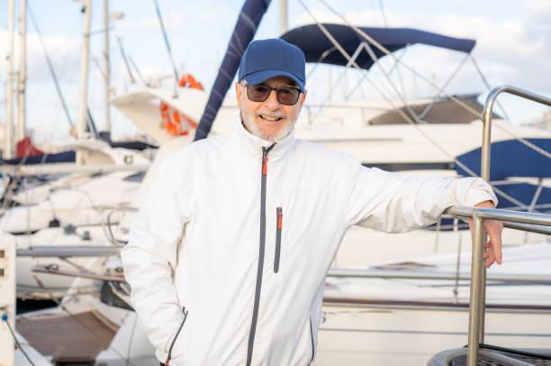 Elderly smiling man wearing cap spending free time walking on marina.