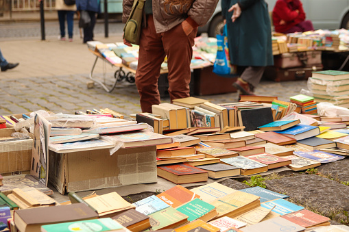 Lviv, Ukraine - 26.09.2021: people buying books in market outside. Old books on a flea market books. Colorful old second hand books in a street. Unrecognizable people doing shopping in background.