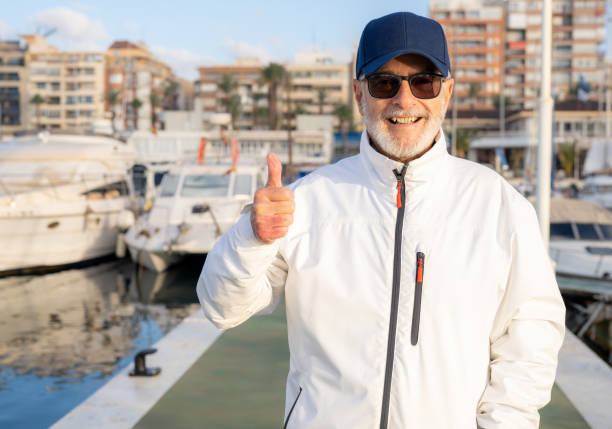 Elderly man spending free time walking on marina and looking sightseeing showing thumb up.