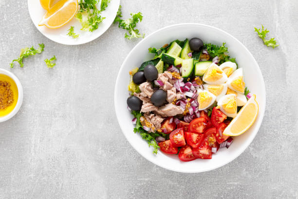 Tuna and fresh vegetable salad of tomato, cucumber, olives, onion, lettuce and boiled egg, top view Tuna and fresh vegetable salad of tomato, cucumber, olives, onion, lettuce and boiled egg, top view salad fruit lettuce spring stock pictures, royalty-free photos & images