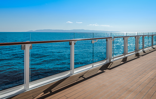 The side of a generic cruise ship sailing along a coastline on a sunny day