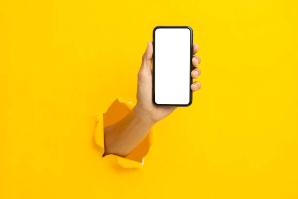 man hand holding a blank screen smart phone on a yellow background"n stock photo