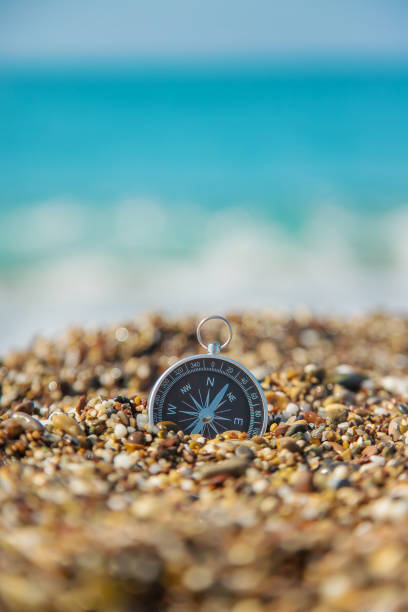 bussola sulla spiaggia del mare. messa a fuoco selettiva. - marine compass selective focus vertical holding foto e immagini stock