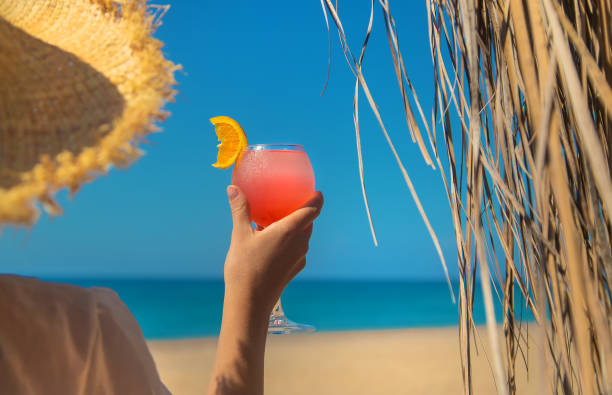 istock Woman on the beach holding a cocktail in her hands. Selective focus. 1364241746