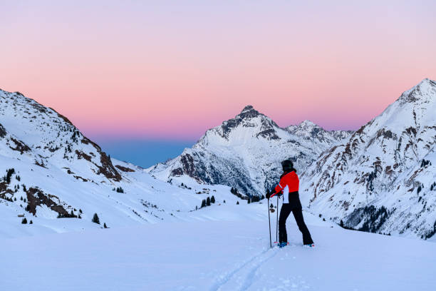 Skier in ski-resort Lech after sunset Skier looking at the landscape in ski-resort Lech after sunset during winter. Vorarlberg, Austria snow sunset winter mountain stock pictures, royalty-free photos & images