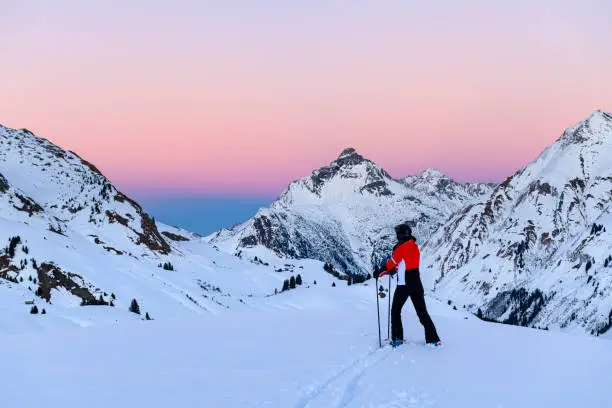 Skier looking at the landscape in ski-resort Lech after sunset during winter. Vorarlberg, Austria