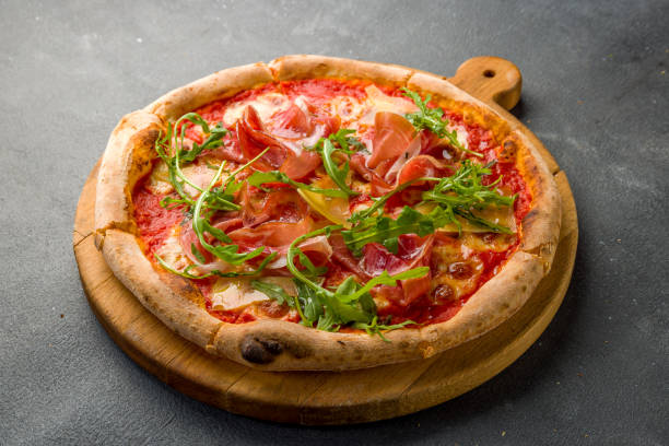 istock Pizza with Parma ham and arugula on the board on grey concrete table 1364248625