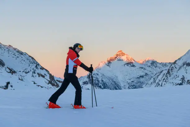Skier looking at camera in ski-resort Lech after sunset during winter. Vorarlberg, Austria