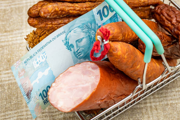 ein miniatur-einkaufswagen voller aufschnitt aller art mit einer brasilianischen 100 reais-banknote, konzept, steigende preise für fleischprodukte während der inflation - real food fotos stock-fotos und bilder