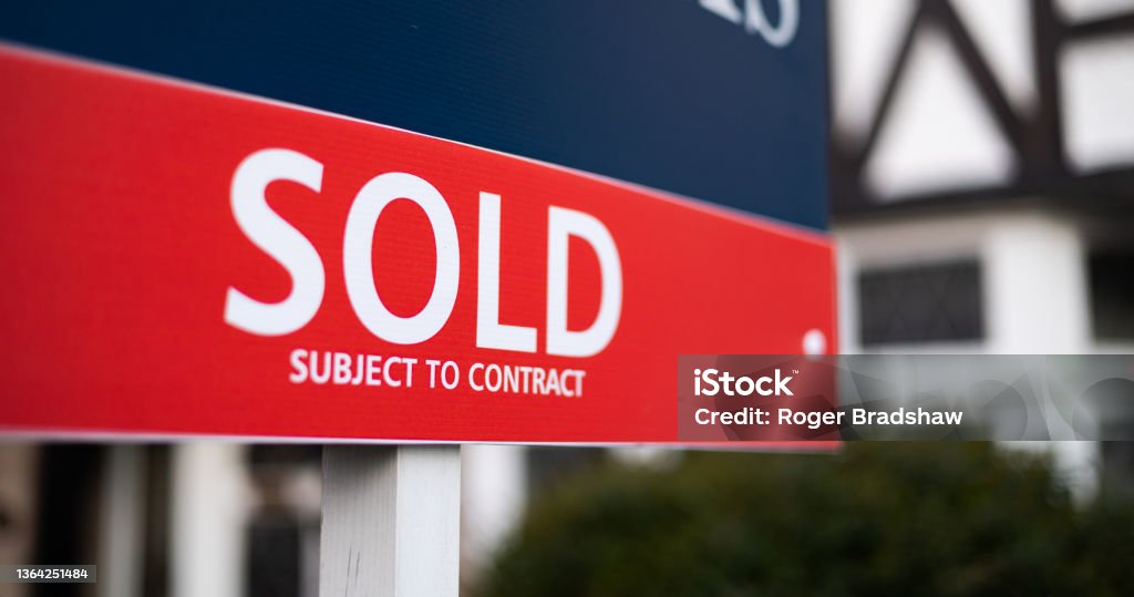 estate agent sold sign close up of sold sign in front of house - narrow depth of field Selling Stock Photo