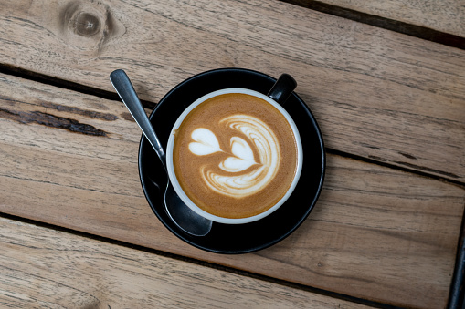 Image of hot latte coffee with latte art on wooden table background.