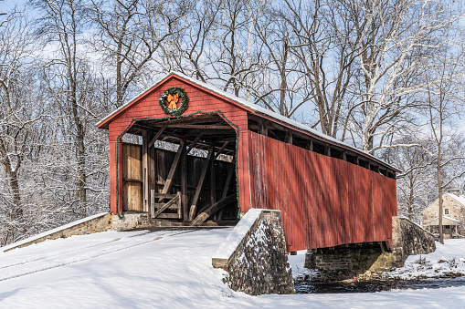 Historic Pool Forge Covered Bridge with snow on a bright winter day in Lancaster County, Pennsylvania, USA