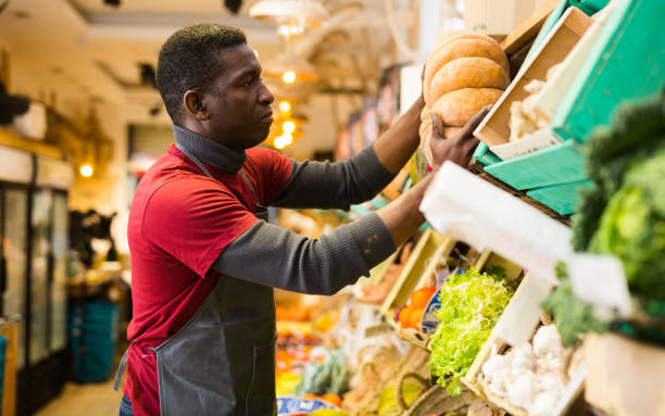 istock Man putting pumpkin on market showcase 1364255265