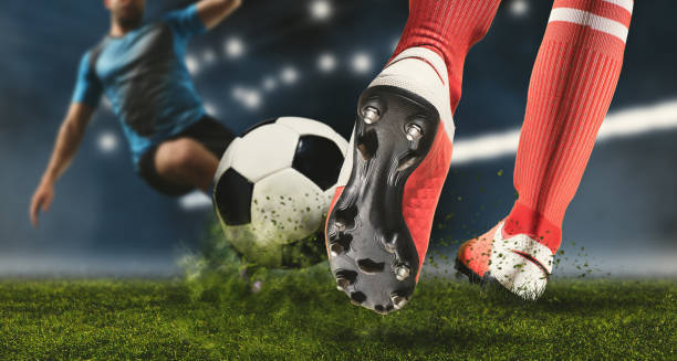 Soccer player making sliding tackle Football player man in action on dark arena background. Soccer player making sliding tackle red boot stock pictures, royalty-free photos & images