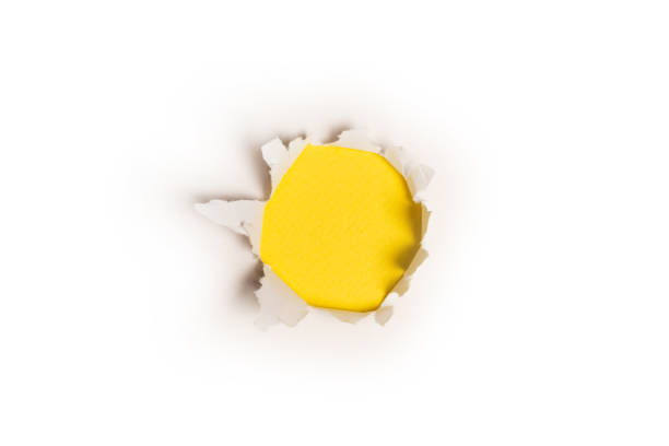 istock A hole in a white paper on a yellow background. 1364257370