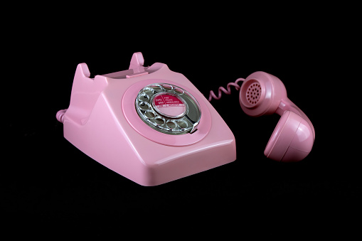 Vintage pink telephone isolated on a black background