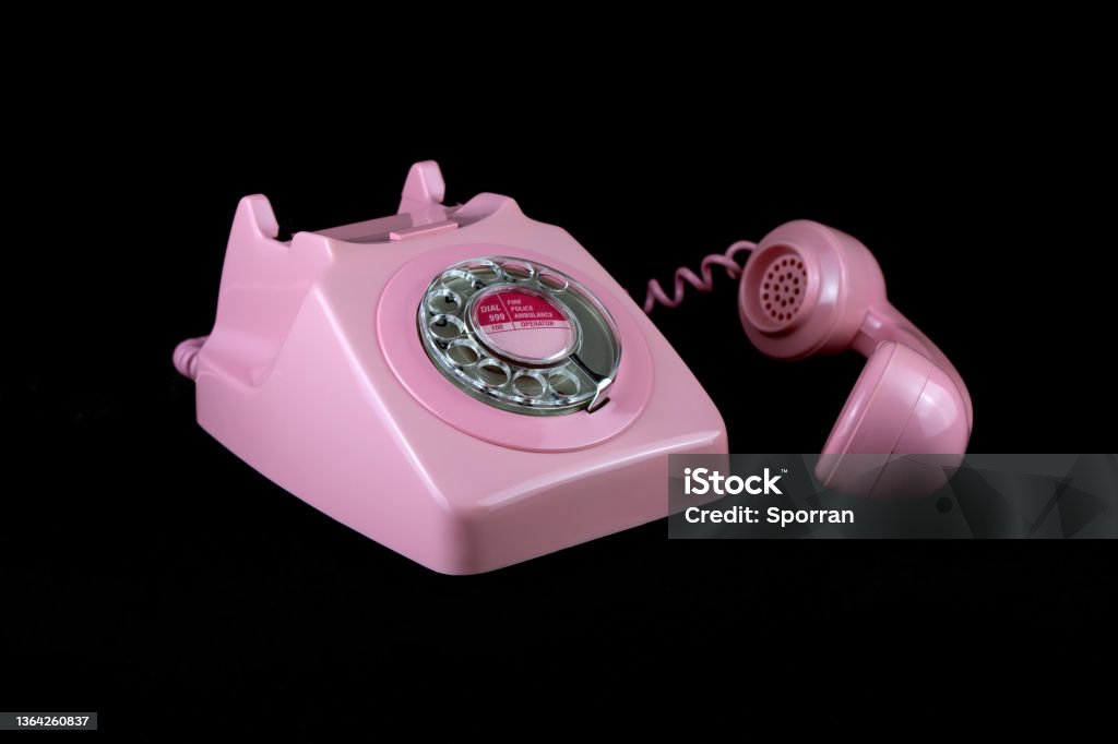 Vintage Pink Telephone on a Black Background Vintage pink telephone isolated on a black background Pink Color Stock Photo