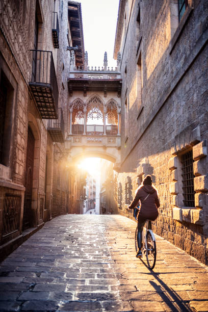 El Pont del Bisbe - Bishop Bridge in Barcelona unrecognizable woman riding a bike in the morning at the gothic quarter of Barcelona narrow photos stock pictures, royalty-free photos & images