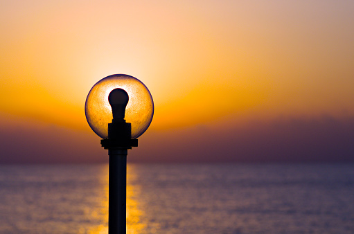 Abstract view of old sphere lantern on the background of the sun disk. Scenic morning landscape view of the sea.  The Mediterranean Sea near Mersin, Turkey. Travel and tourism concept.
