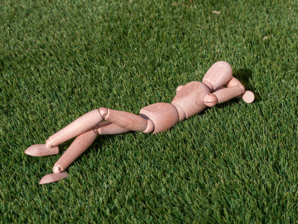 istock Wooden doll lying on the grass relaxed sunbathing 1364268918