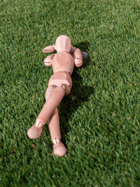 istock Wooden doll lying on the grass relaxed sunbathing 1364268919