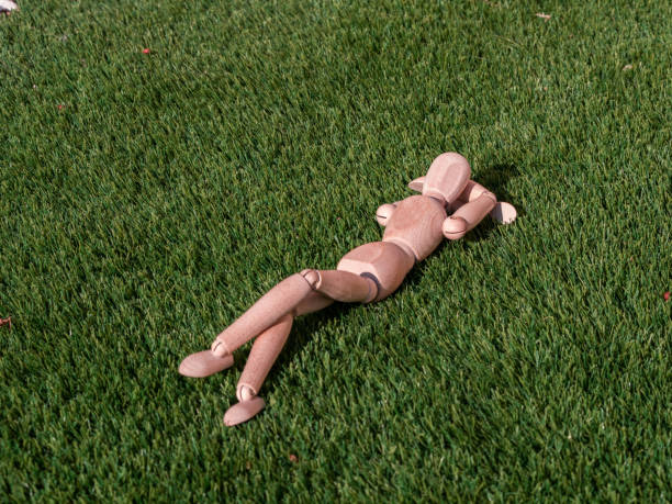 istock Wooden doll lying on the grass relaxed sunbathing 1364268933
