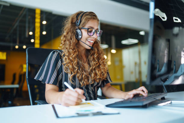 Call center agent with headset working on support hotline in modern office. stock photo