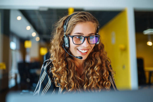 istock Call center agent with headset working on support hotline in modern office. 1364269966