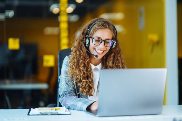 call center agent with headset working on support hotline in modern office. - verkoopster stockfoto's en -beelden