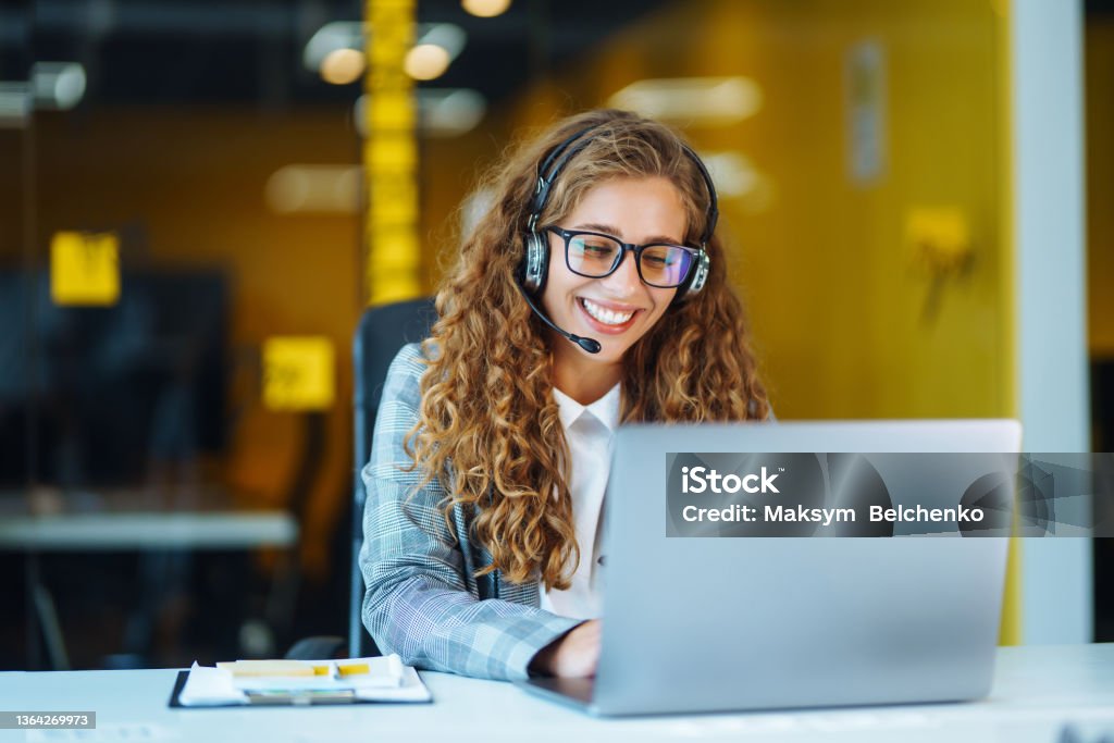 Call center agent with headset working on support hotline in modern office. Call center agent with headset working on support hotline in modern office. Video conference.  Оnline training. Call Center Stock Photo