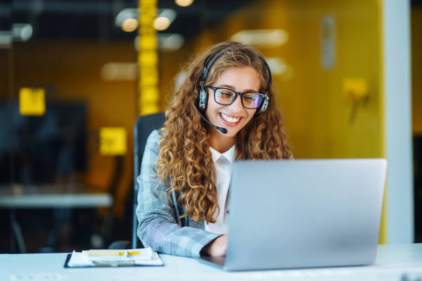Call center agent with headset working on support hotline in modern office. Call center agent with headset working on support hotline in modern office. Video conference.  Оnline training. customer service stock pictures, royalty-free photos & images