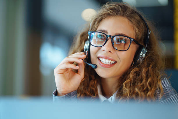 Call center agent with headset working on support hotline in modern office. stock photo