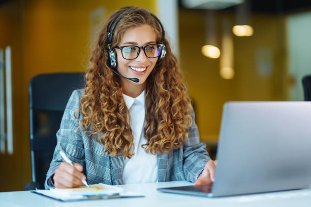 istock Call center agent with headset working on support hotline in modern office. 1364270001