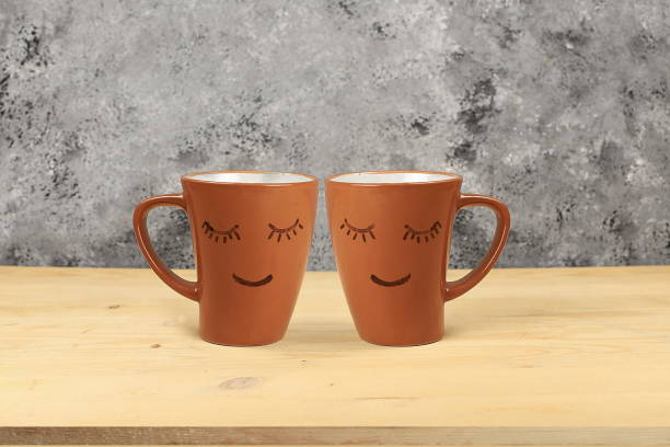 istock Empty wooden table with coffee mugs with funny faces,friendship day concept,.Kitchen interior,design and product showcase mockup, 1364270028