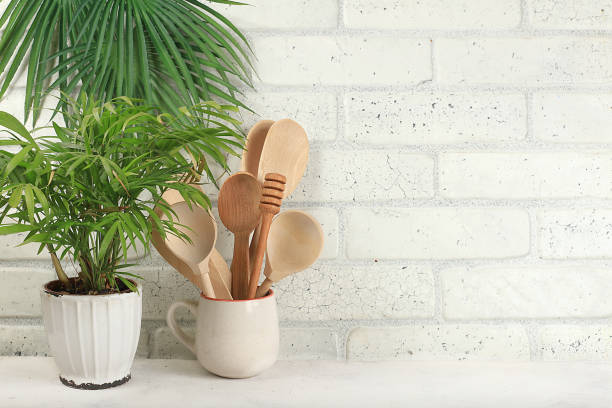 istock Empty table with wooden appliances, utensils and palm leaves. Kitchen interior, mockup for design and product showcase, 1364270034