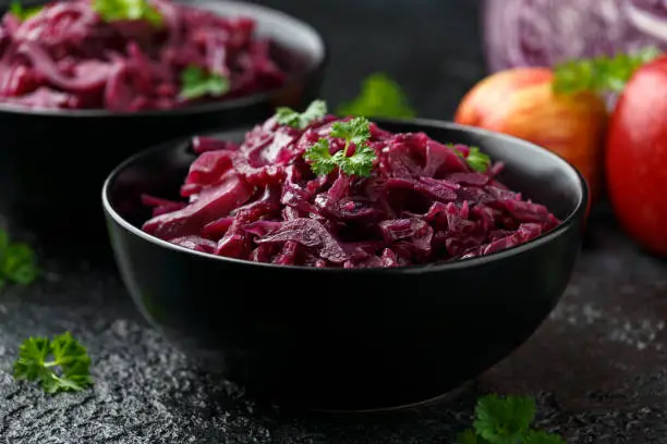 Braised Red Cabbage with apples and redcurrant in black bowl.