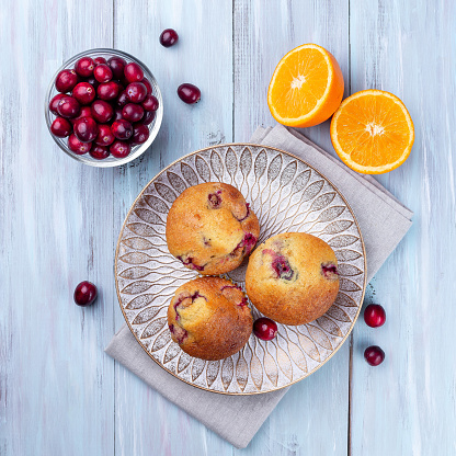 Homemade cranberry orange muffins on a wooden plate, top view, square format